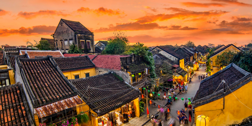這張圖片拍攝於越南會安（Hoi An）古鎮，黃昏時分的街道燈火通明，紅瓦屋頂與古色古香的建築展現出濃厚的歷史氛圍。街上人潮湧動，燈籠點綴街道，使整個場景充滿浪漫與懷舊氣息。會安是世界文化遺產，以其獨特的建築風格、夜市與河畔風光聞名，是越南旅遊的熱門景點之一。