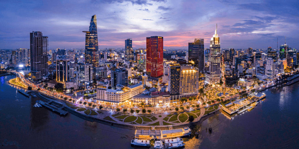 這張圖片展示了越南胡志明市（Ho Chi Minh City）的天際線。高樓大廈和繁忙的街道展示了這座城市的現代化與活力，夜幕降臨時，城市燈光閃爍，創造出一幅繁華的都市畫面。